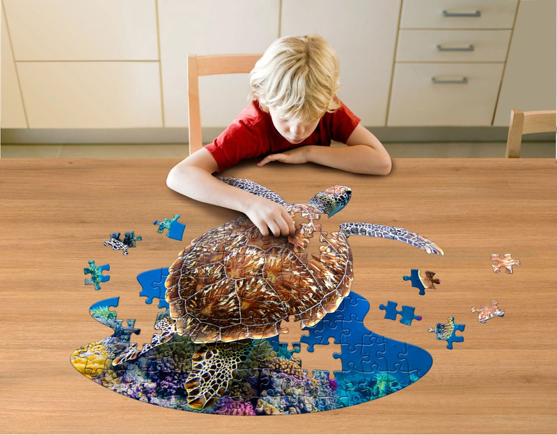 Child assembling sea turtle-shaped puzzle on a wooden table.