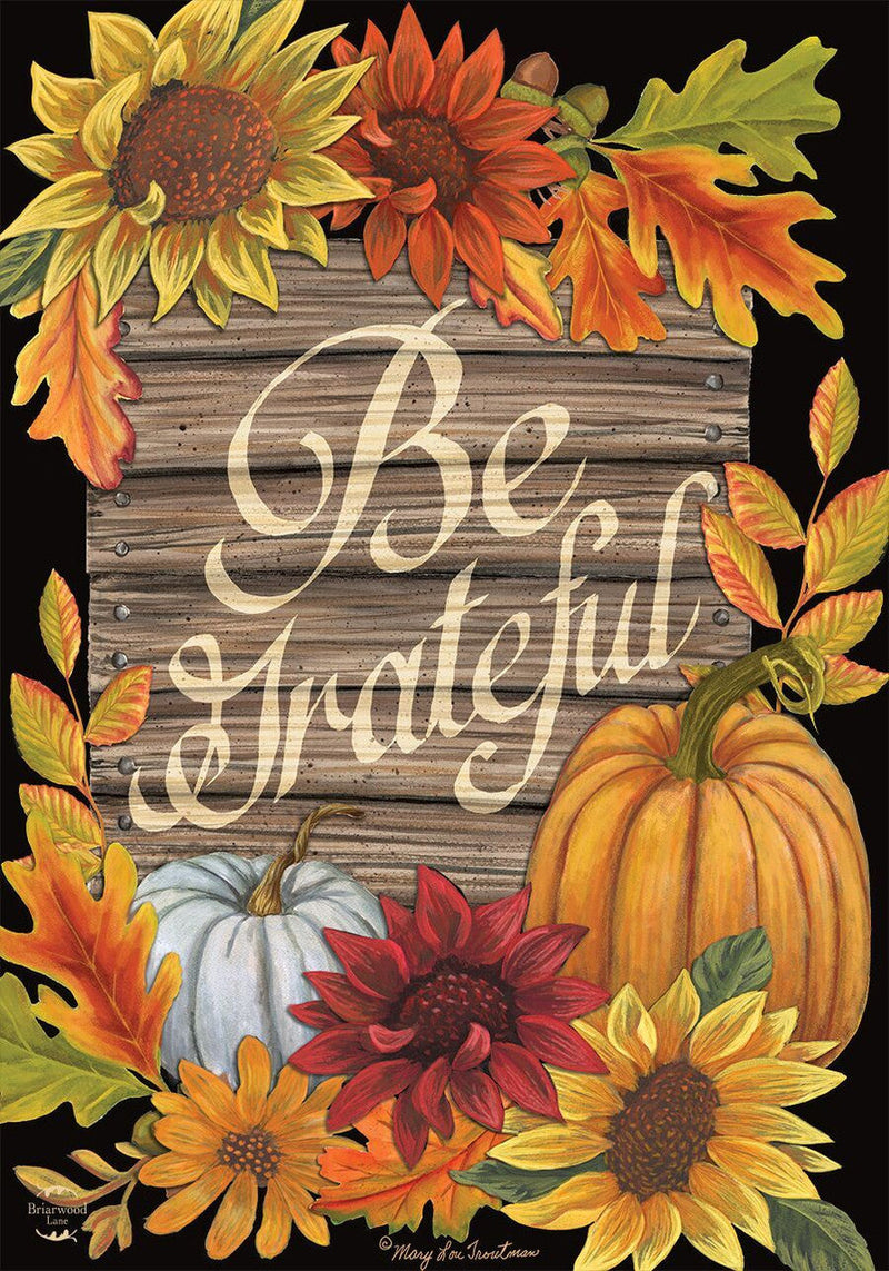 Decorative sign with autumn elements and 'Be Grateful' text on a black background.