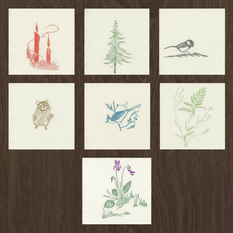 example of all napkins with Gwen Frostic illustrations on a wood grain background