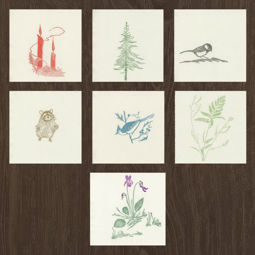 example of all napkins with Gwen Frostic illustrations on a wood grain background