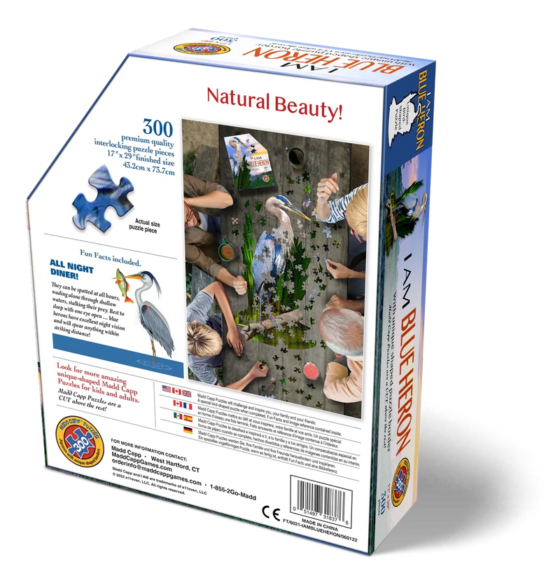 Jigsaw puzzle packaging with people interacting with a blue heron puzzle, featuring text and branding.
