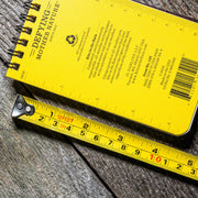 Yellow notebook with text and a ruler on a wooden surface