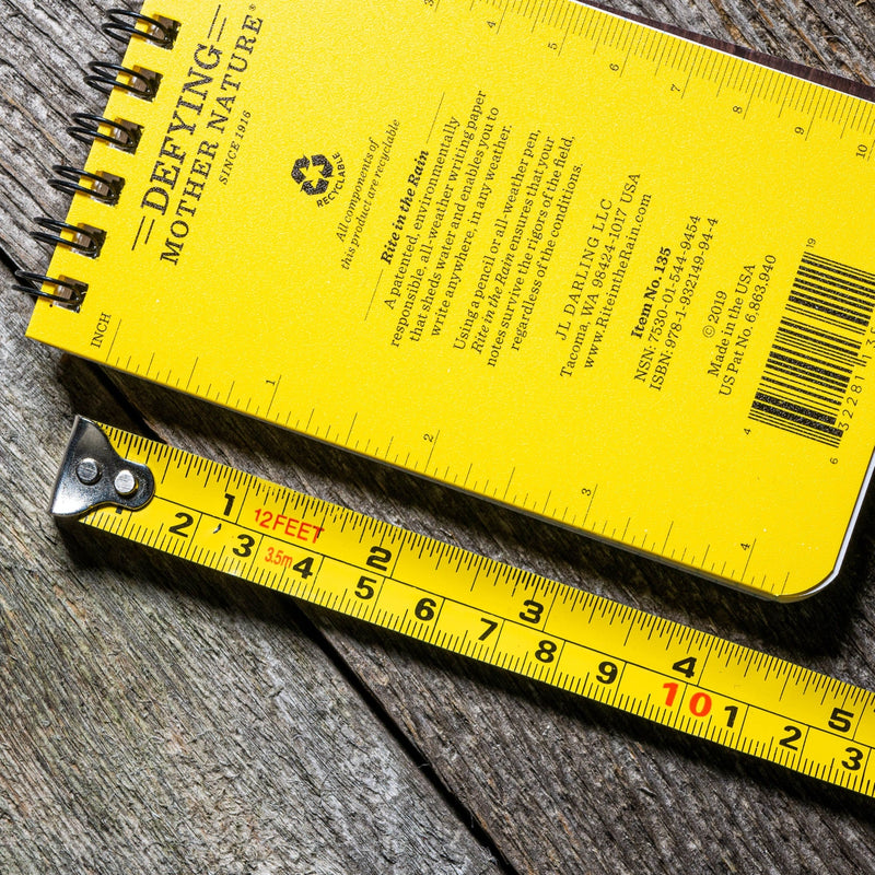 Yellow notebook with text and a ruler on a wooden surface