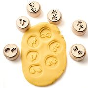 Set of animal footprint wooden stamps with examples on yellow dough on a white background