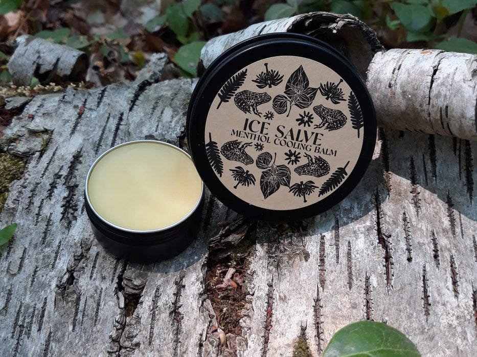 Ice Salve Menthol Cooling Balm 2oz with lid off on birch log