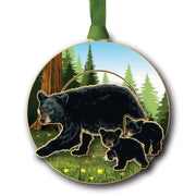 Circular ornament with a black bear and cubs in a forest scene, hanging on a green ribbon.