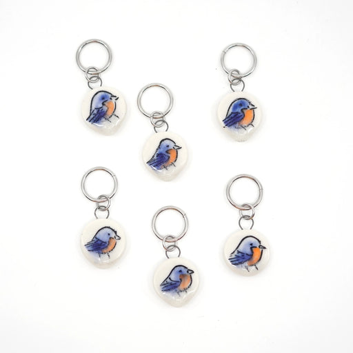 Set of six bluebird-themed ceramic stitch markers on a white background