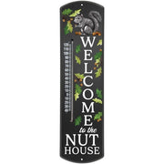 Nut house thermometer with black background and white text that rats: "welcome to the nut house" featuring a grey squirrel, acorns and oak leaves. 
