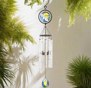 Decorative wind chime with stained glass design hanging against a light background with greenery.