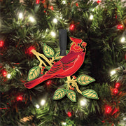 Red cardinal bird ornament on a holiday tree with lights and decorations.