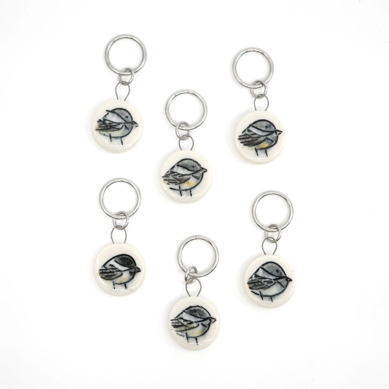 Set of six chickadee-themed ceramic stitch markers on a white background