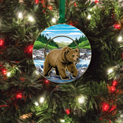 Round Christmas ornament with a  grizzly bear design on a tree with lights.