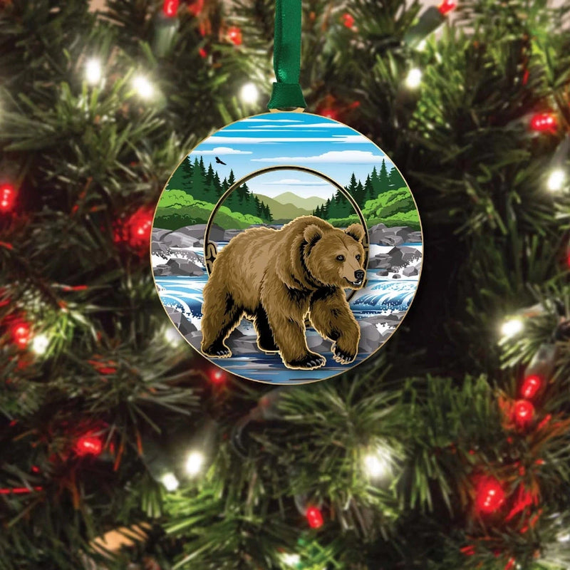 Round Christmas ornament with a  grizzly bear design on a tree with lights.
