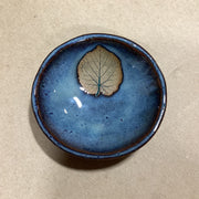 Blue ceramic dish with an embossed basswood leaf on a beige background