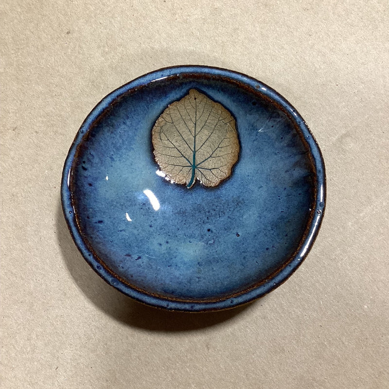 Blue ceramic dish with an embossed basswood leaf on a beige background