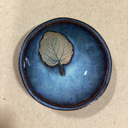 Blue ceramic bowl with an embossed  leaf on a beige background