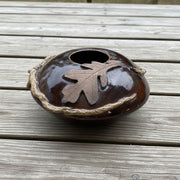 brown ceramic vase with oak leaf design on a picnic table