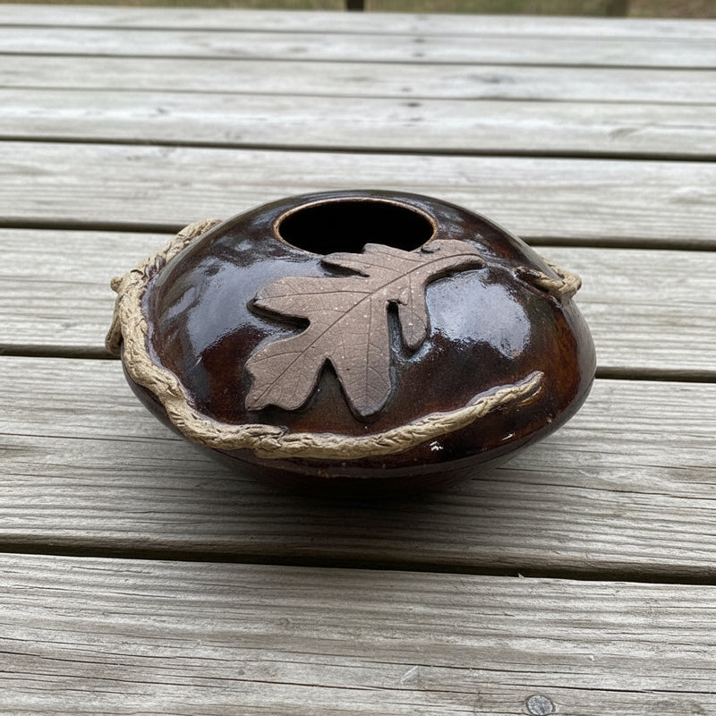 brown ceramic vase with oak leaf design on a picnic table