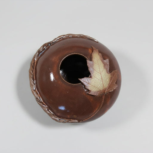 Brown ceramic pillow vase with a maple leaf on top