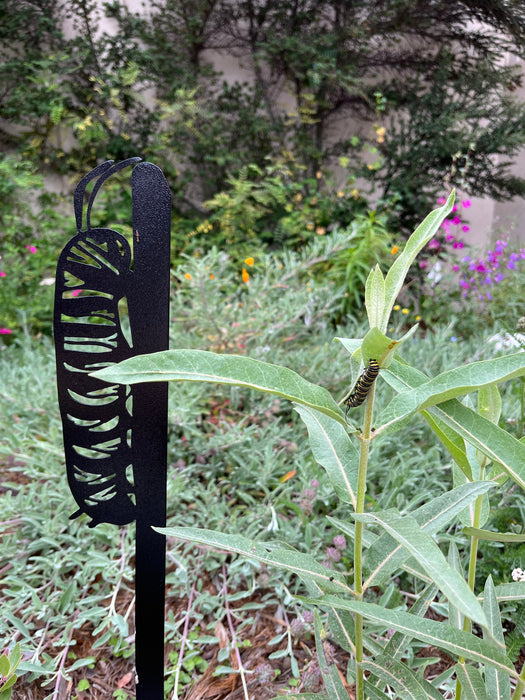Monarch caterpillar stake in a garden with a real monarch caterpillar nearby