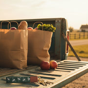 Keychain with bee pattern on a light green strap placed on a tailgate with bagged groceries