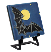 Decorative tile with a black bat design displayed on a metal easel 