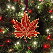 Red maple leaf ornament on a Christmas tree with lights