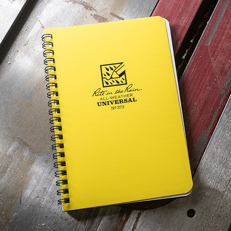 Yellow notebook with 'Rite in the Rain' branding on a wooden surface