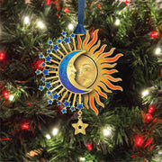 Decorative sun and moon ornament with stars on a Christmas tree.