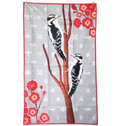 One side of tea towel, design features with two woodpeckers on a branch and red flowers on a gray background