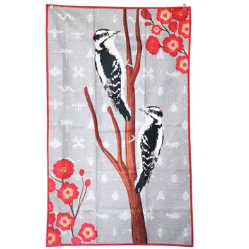 One side of tea towel, design features with two woodpeckers on a branch and red flowers on a gray background