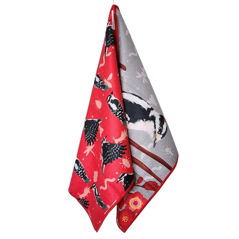 Reversible towel hanging to display  with black and white woodpecker  patterns on a white background