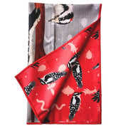 Folded tea towel with woodpecker pattern on a red background