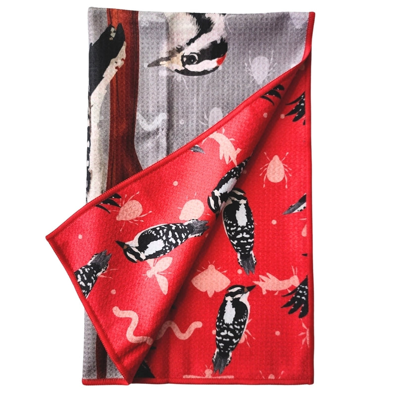 Folded tea towel with woodpecker pattern on a red background