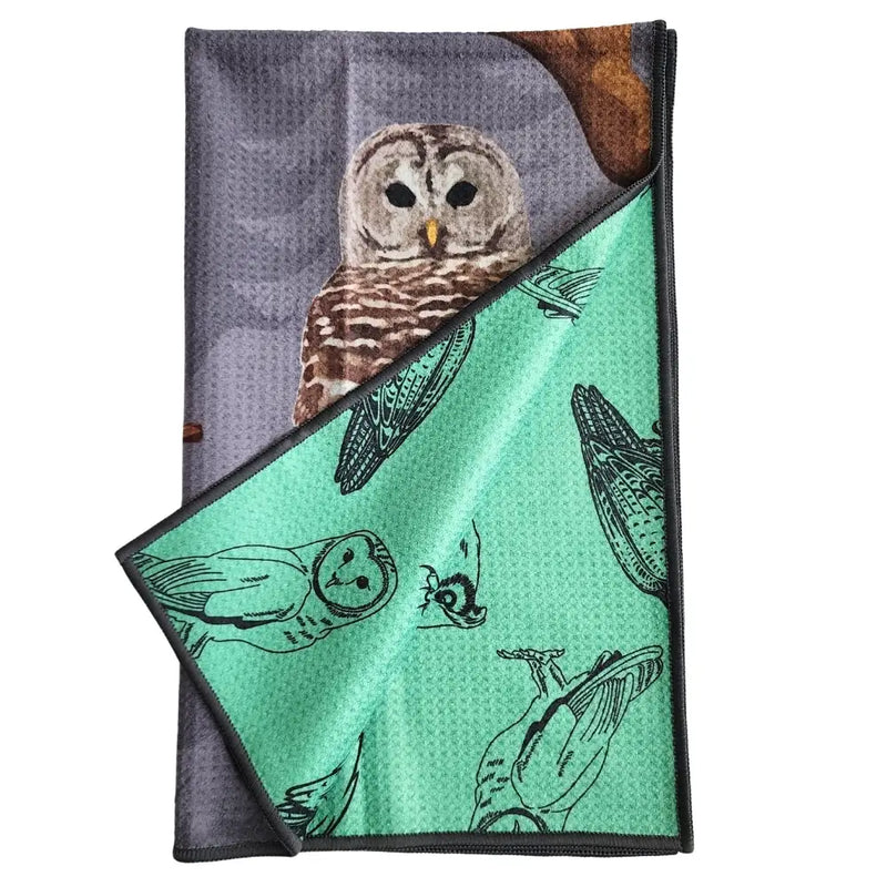 Folded reversible tea towel with owl design on a white background