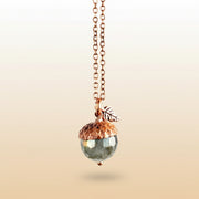 Necklace with acorn pendant and coin charm on a neutral background