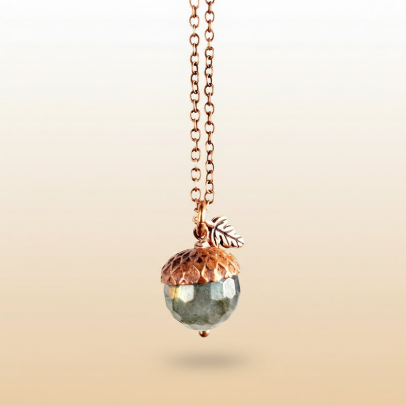 Necklace with acorn pendant and coin charm on a neutral background