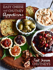 Appetizers with cheese, chutney, and olives on a wooden board with Tait Farm Chutneys branding.