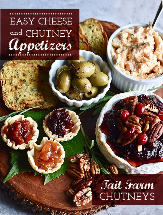 Appetizers with cheese, chutney, and olives on a wooden board with Tait Farm Chutneys branding.
