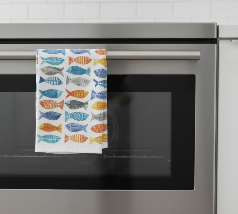 kitchen towel with fish prints hanging off an oven door