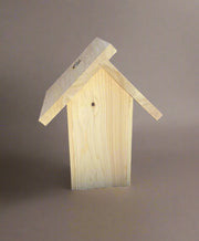 Back of wooden birdhouse with a slanted roof on a neutral background