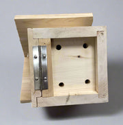Bottom of wooden birdhouse with a metal hinge on a neutral background