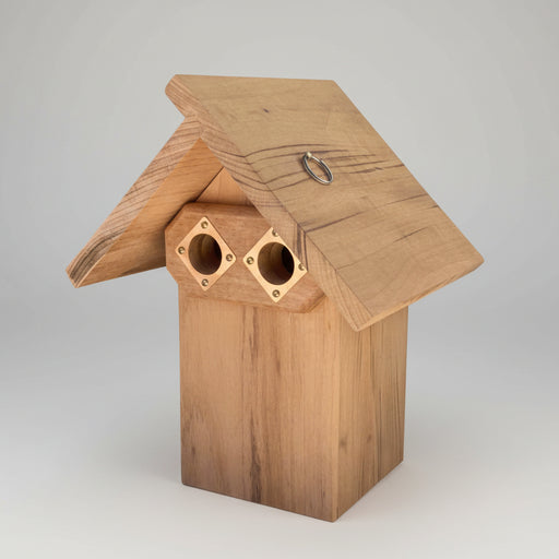 Wooden double-portal bluebird nest box with a rustic design on a wooden surface.