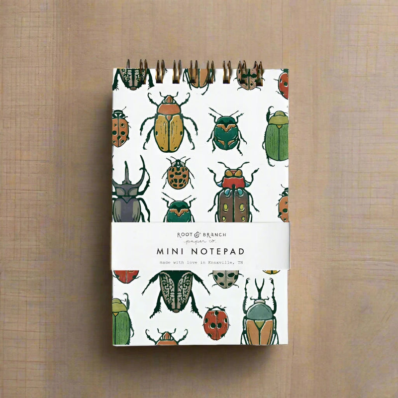 Mini notepad with beetle illustrations on a wooden surface