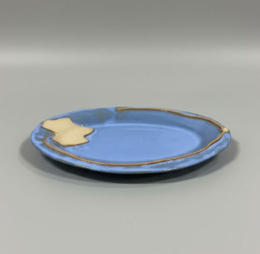 Blue ceramic plate with rustic leaf rim on a gray background