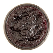 Top view of a jar of dark purple jam on a white background