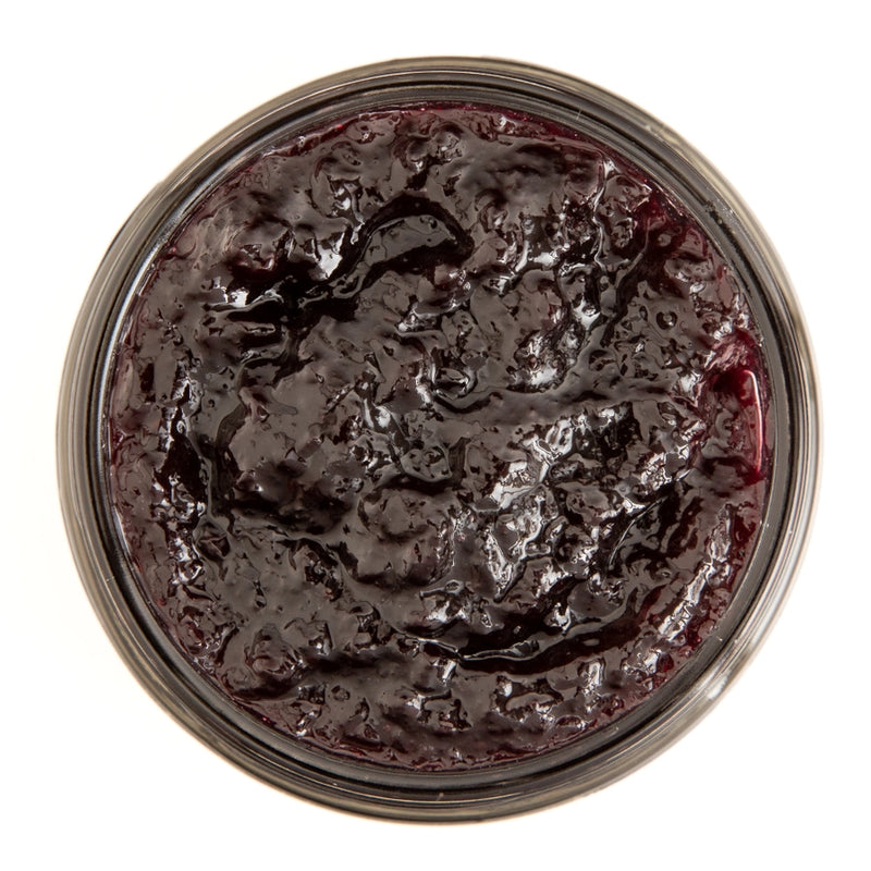 Top view of a jar of dark purple jam on a white background