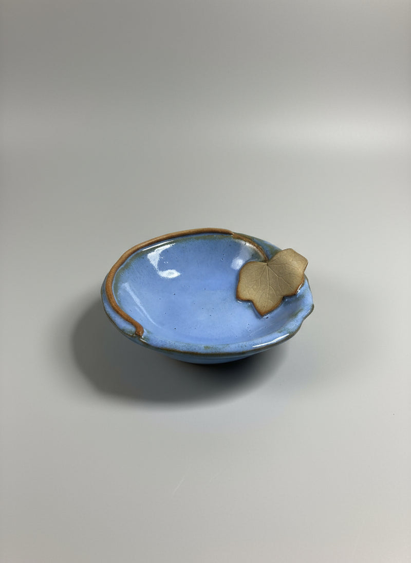 Small blue ceramic dish with a rustic leaf trim on a gray background