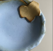 Blue ceramic bowl with a leaf-shaped accent on a grey surface