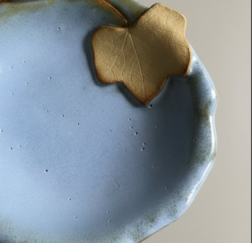 Blue ceramic bowl with a leaf-shaped accent on a grey surface